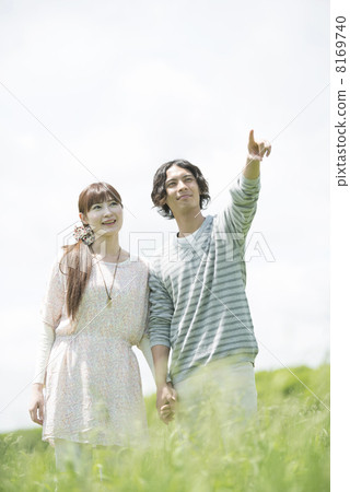 A couple smiling a hand holding hands in the field 8169740