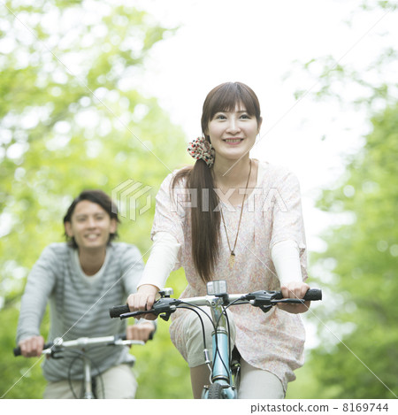 A couple riding a bicycle in fresh green 8169744