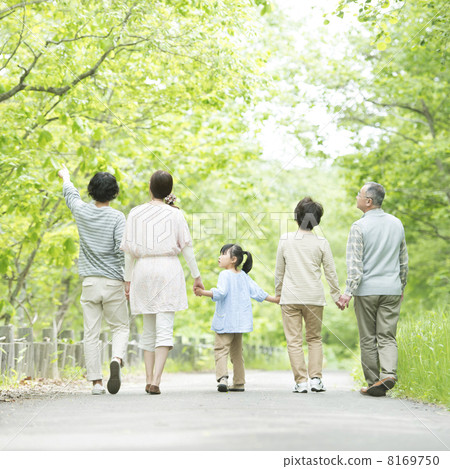 The back of the 3 generations family holding hands in fresh green 8169750
