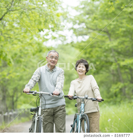 Senior couple who push a bicycle in fresh green 8169777