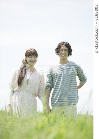 A couple smiling a hand holding hands in the field 8169808
