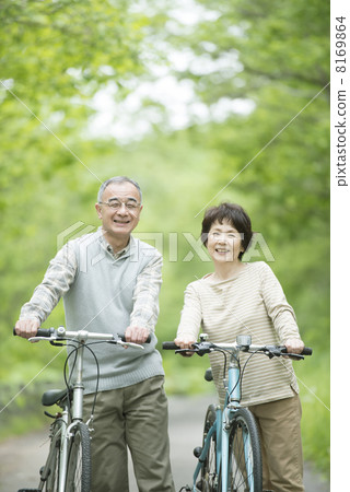 Senior couple who push a bicycle in fresh green 8169864