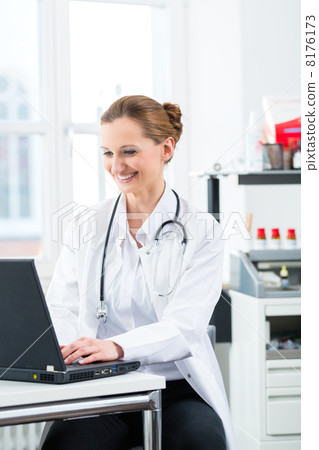 Female doctor writing on Pc in her clinic 8176173