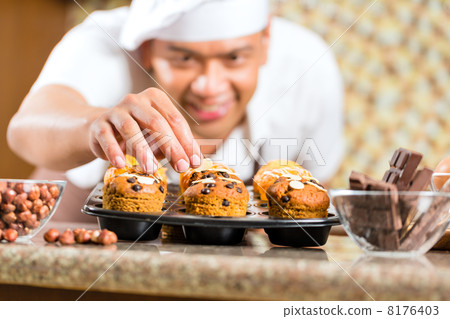 Asian man baking muffins in home kitchen 8176403