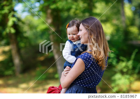 Beautiful mother and little daughter walking in summer park 8185967