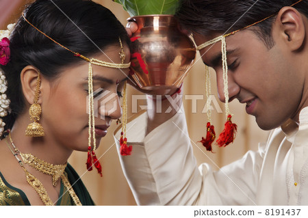 Young Maharashtrian bride and groom performing rituals together Young Maharashtrian bride and groom performing rituals together 8191437
