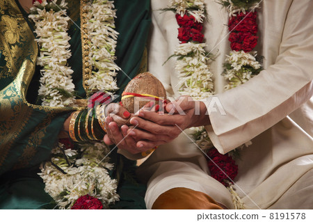 Mid section of bride and groom holding coconut together Mid section of bride and groom holding coconut together 8191578