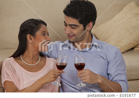 圖庫照片: smiling young couple holding wineglass while looking