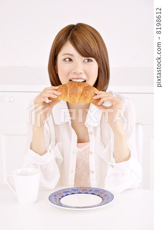 A woman eating a croissant A woman eating a croissant 8198612