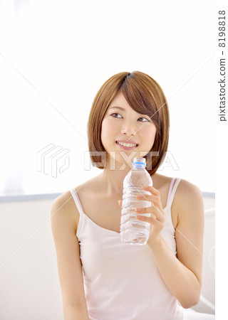 A woman drinking water with a bed 8198818