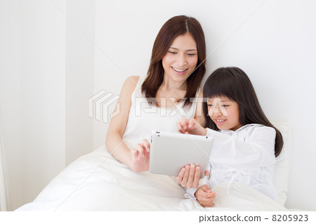Parents and children watching tablets in bed Parents and children watching tablets in bed 8205923