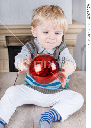 Little toddler playing with red Christmas tree ball 8207979