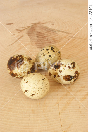 four organic quail eggs on a timber board 8222141
