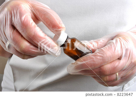 Health care staff with disposable glove open pill bottle 8223647
