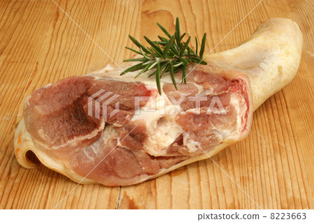 raw knuckle of pork with rosemary on a wooden board 8223663