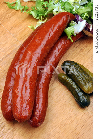 smoked sausage and organic gherkin on a timber board smoked sausage and organic gherkin on a timber board 8223739