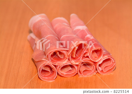 sliced ham rolled on a timber plate 8225514