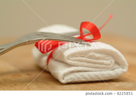Fork and knife with a white serviertte and red ribbon Fork and knife with a white serviertte and red ribbon 8225851