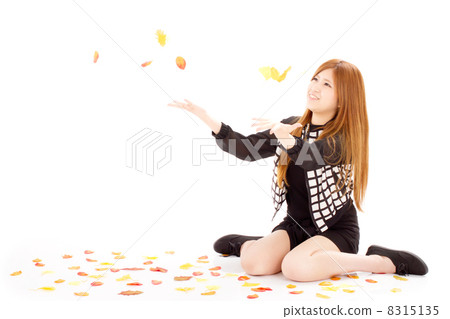 坐很多下落的葉子和相當使用的青少年的逗人喜愛的女孩 坐很多下落的葉子和相當使用的青少年的逗人喜愛的女孩 8315135