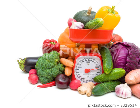 vegetables and kitchen scales closeup on a white background vegetables and kitchen scales closeup on a white background 8329534