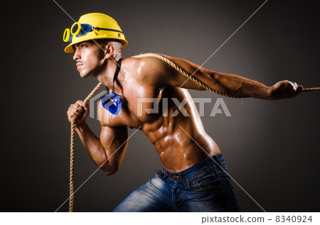 Nude builder pulling rope in darkness 8340924