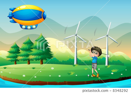 A boy playing golf in the field with windmills A boy playing golf in the field with windmills 8348292