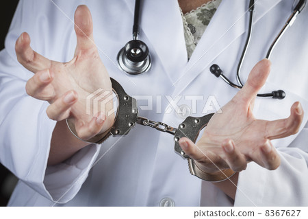 Doctor or Nurse In Handcuffs Wearing Lab Coat and Stethoscope Doctor or Nurse In Handcuffs Wearing Lab Coat and Stethoscope 8367627