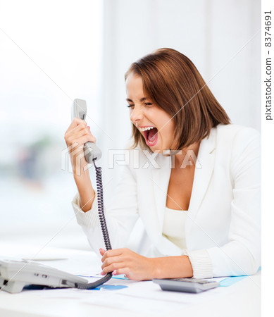woman shouting into phone in office woman shouting into phone in office 8374691