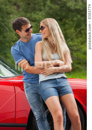 Smiling couple hugging and leaning against cabriolet Smiling couple hugging and leaning against cabriolet 8383774