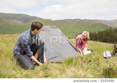Happy couple pitching their tent Happy couple pitching their tent 8383990
