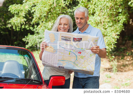 Smiling mature couple reading map Smiling mature couple reading map 8384680