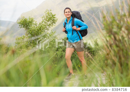 Female hiker with backpack walking and smiling Female hiker with backpack walking and smiling 8384716