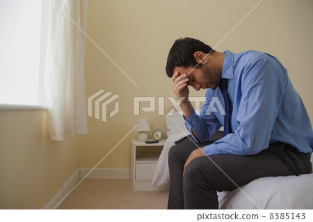 Mournful man sitting head in hands on his bed 8385143