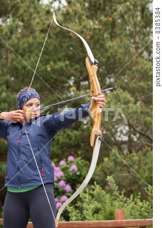 Focused brunette practicing archery 8385384