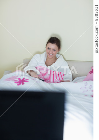 Laughing teen wearing bathrobe watching tv 8385611