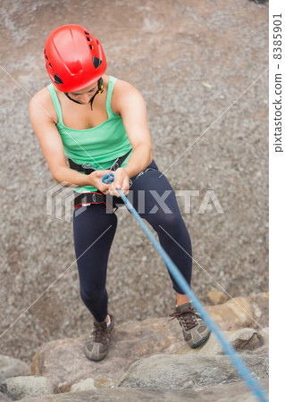 Sporty girl abseiling down rock face 8385901