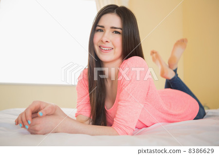 Smiling girl looking at camera lying on her bed Smiling girl looking at camera lying on her bed 8386629