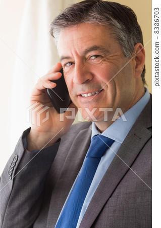 Smiling man calling someone with his mobile phone Smiling man calling someone with his mobile phone 8386703