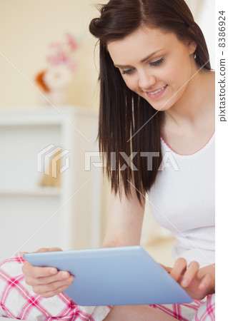 Happy girl sitting on bed using tablet 8386924