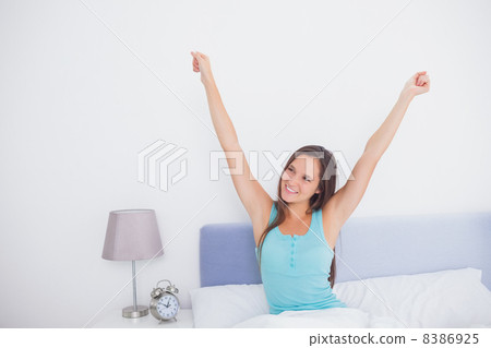 Brunette woman stretching her arms in bed in the morning 8386925