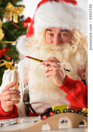 Santa Claus in his workshop making new toys 8402588