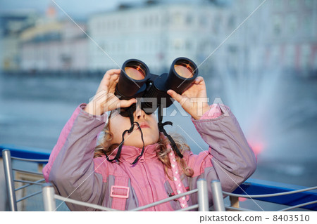 Little girl looks through binoculars at the sunset, standing on Little girl looks through binoculars at the sunset, standing on 8403510