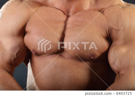 Strong chest and hand muscles of undressed tanned wet bodybuilde 8403725