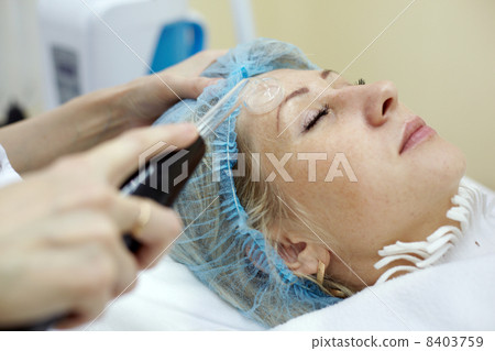 Woman in beauty salon gets face skin treatment with the device o 8403759