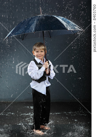 smiling boy dressed in white shirt standing under umbrella in ra 8403760