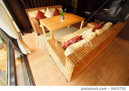 Two wicker couches with pillows and table in empty comfortable r 8403792