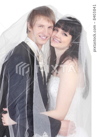 Happy young groom and bride hide under transparent veil isolated 8403841