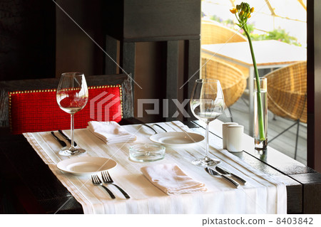 serving at table with white tablecloth and red chair in empty re 8403842