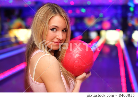 smiling girl with red ball stands in bowling club and preparing 8403935