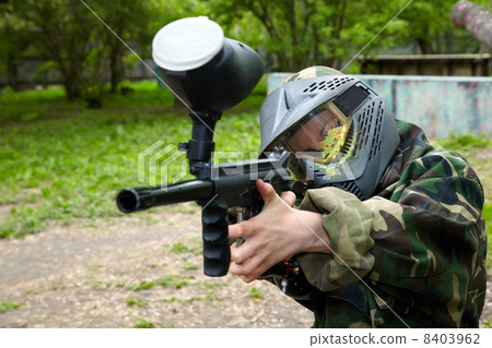 Paintball player in camouflage uniform and protective mask with 8403962